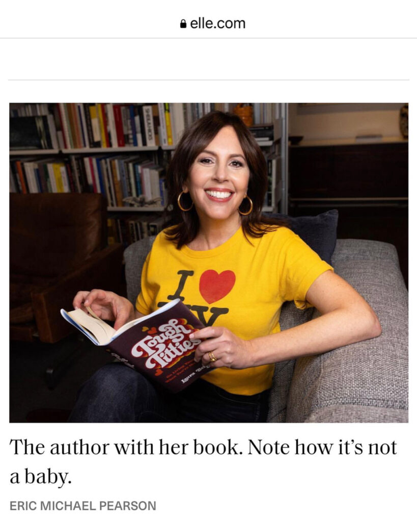 Laura Belgray holding her book, Tough Titties, as featured in Elle Magazine. Caption reads: The Author with her book. Note how it's not a baby. Photo credit: Eric Michael Pearson